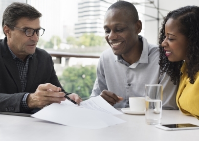 black couple with a financial advisor showing them documents in a coffee setting 